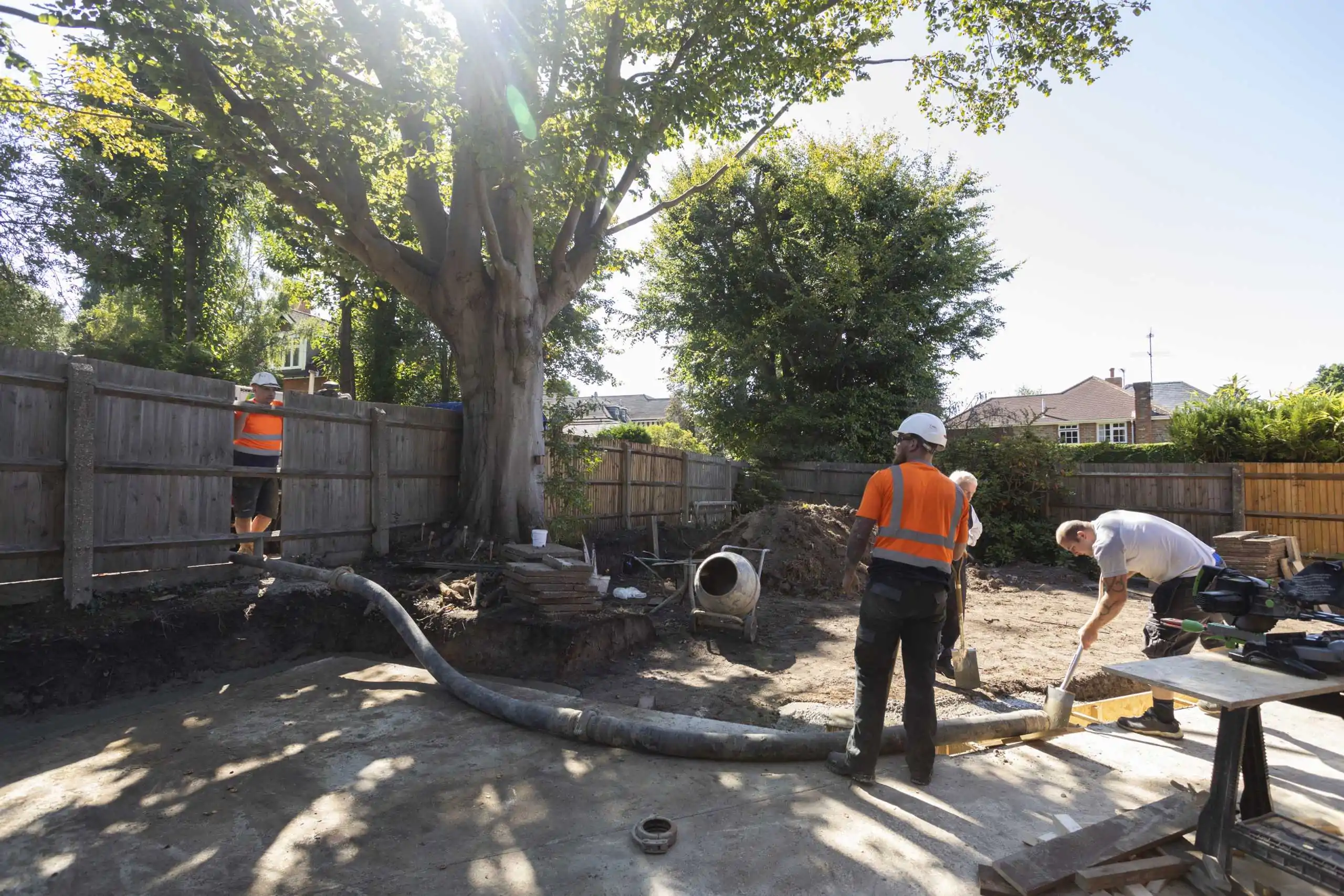 Line pump services running hose through tight access for backyard concrete pour